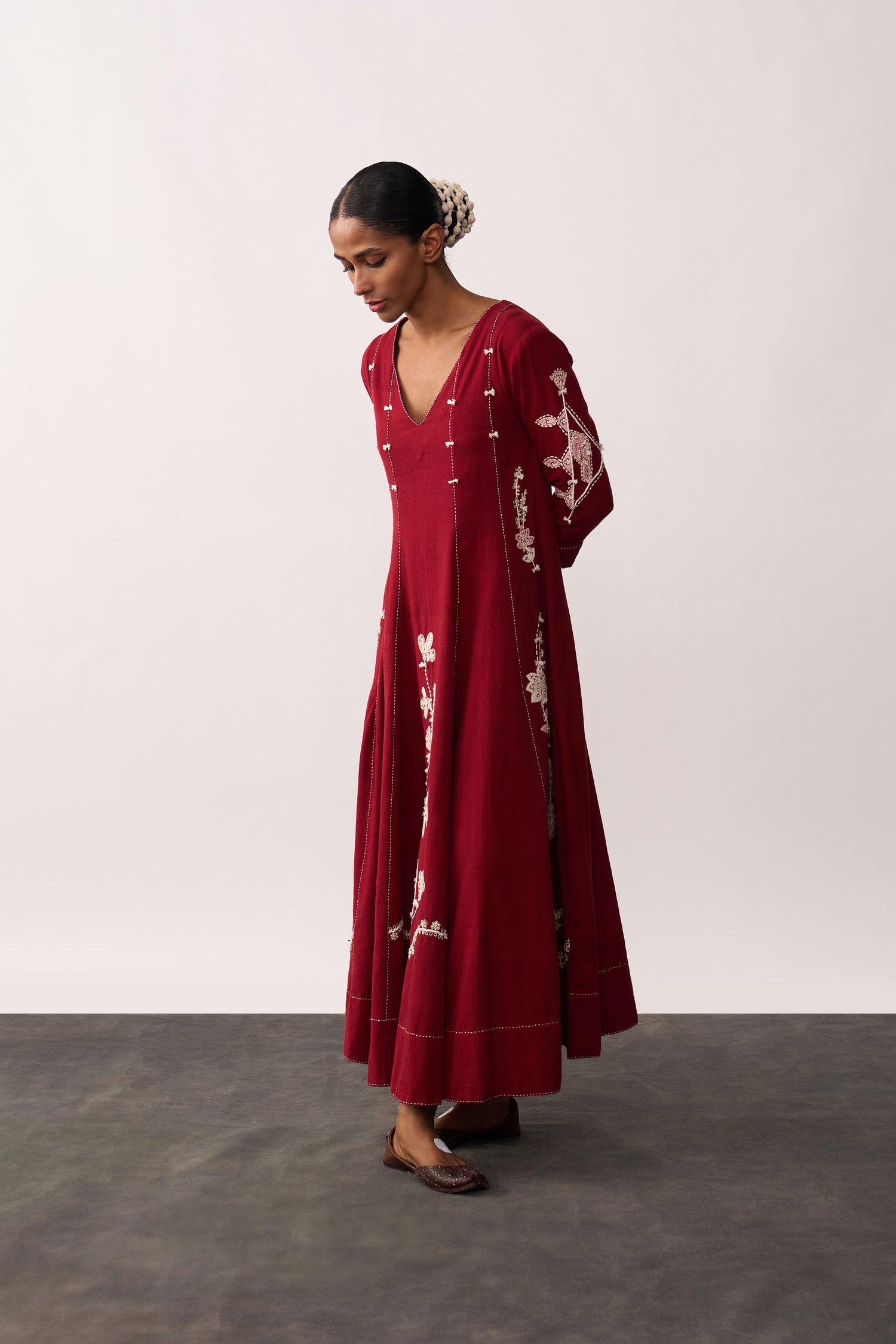 Woman wearing a long red dress with white patterns on a plain background
